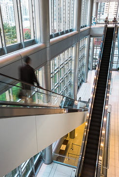 Photo of a blurred figure descending a linear escalator.